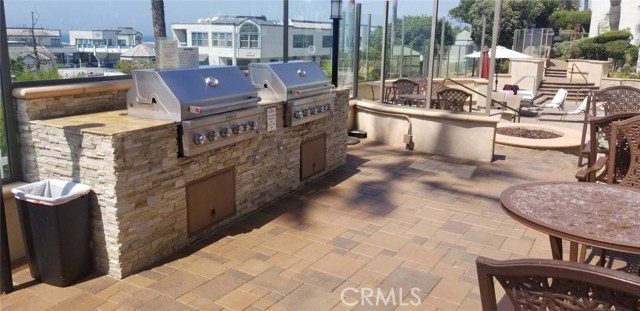 NEWER STAINLESS STEEL BAR-B-QUES AND FIREPIT SEATING AREA IN THE FOREGROUND