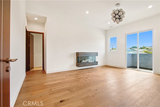 Expansive Master Suite with a floating glass fireplace and balcony with slider