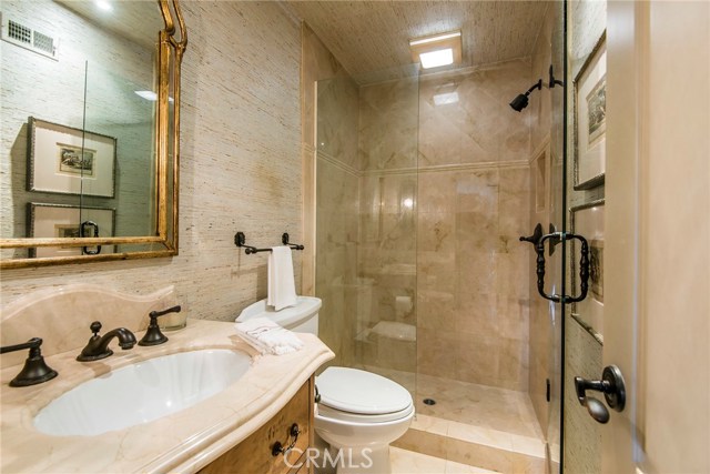 Gorgeous upper guest bath is beautifully appointed with grass cloth wall covering, natural stone tile and bronze finish fixtures. The finest finishes to offer your guests will make you proud to call this your home. Conveniently located near the entry level bedroom.