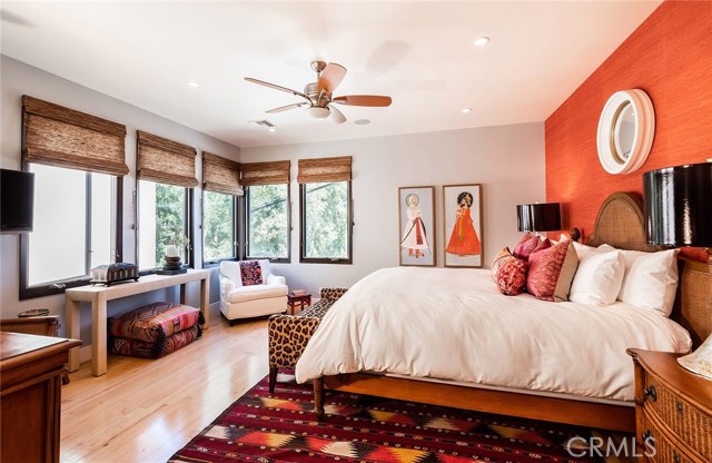 Fun colorful Master Suite with grass cloth wallpaper, wood floors and a bank of windows with woven woods.