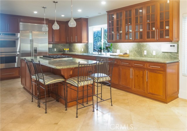 Chefs kitchen with granite counters, center island with Viking 6 burner cooktop, bar stool seating, and plenty of cabinets.