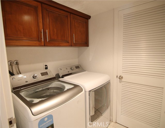 Inside laundry room with upgraded cabinets and additional closet storage room.