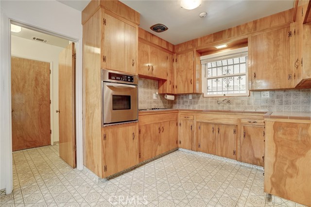 The kitchen features original natural wood cabinets. The oven is newer and the stove is an electric range.