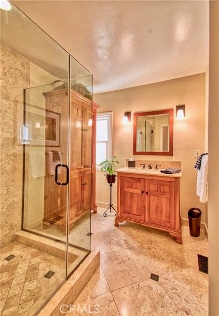 main level bath with custom vanilty, cabinetry & seamless over-sized shower