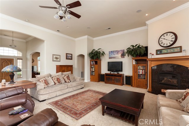 Great room with gas fireplace, ceiling fan, recess lighting, crown moldings, high ceilings.