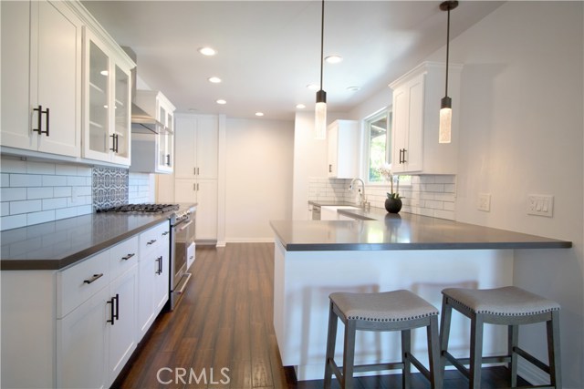 Kitchen boasts white cabinetry w/self-closing drawers & doors, gray quartz counter-tops, Kitchen Aid appliances/including microwave drawer, gorgeous large farm sink, recessed lighting, decorative tiles w/Spanish flair over stove and an Island area which opens to the dining room.