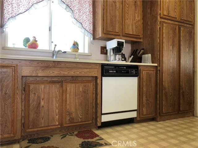 Kitchen with linoleum flooring, dish washer, garbage disposal and wood cabinetry.