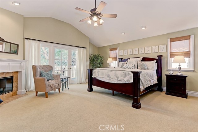 Spacious master bedroom with ceiling fan and fireplace.