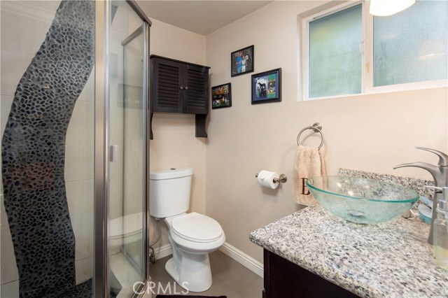 The master bathroom, en-suite with stylish finishes including granite counter vanity, contemporary lighting, and cool tile-work.