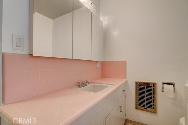 Hall bathroom features an updated mirrored medicine cabinet and 50's style tile counter.