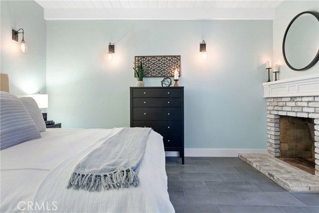 The primary bedroom suite is tranquil and complete with a fireplace, open beamed ceilings, decorative lighting, and thoughtfully spacious closet and storage.