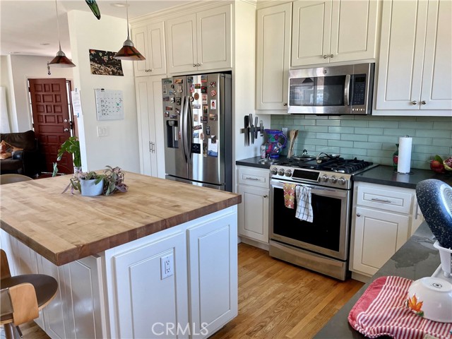 Kitchen with great butcher block island, stainless steel appliances, and beautiful tiled backsplash