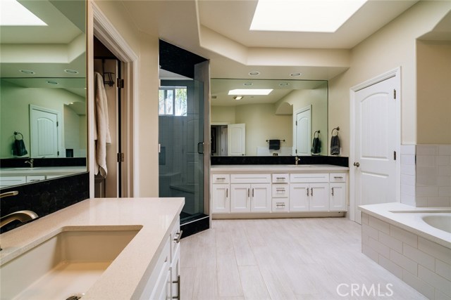 Master bath with dual vanities, soaking tub next to fireplace, and walk-in shower.