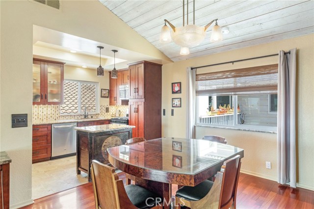 Looking into the kitchen area with cherry wood cabinetry, tile floors, granite counters and stainless appliances.