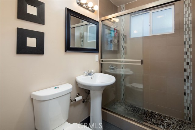 Bathroom #2 with extra large shower is tastefully designed with pedestal sink and contemporary tilework.