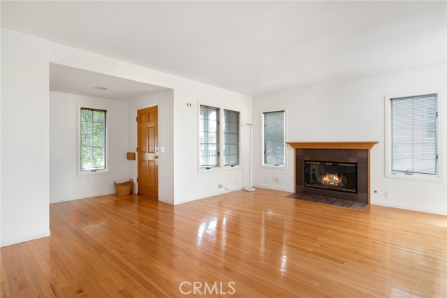 Front entry door and living room with large wood burning and gas fireplace. All first level floors have re-lacquered oak hardwood floors except bedroom which has new carpeting. Note all the windows! They are all dual paned.