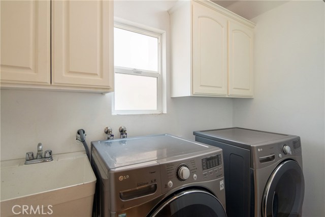 The laundry room with utility sink and cabinetry is an added convenience.