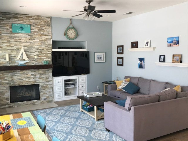 Living room w/fireplace, built in cabinets, stacked stone ceiling fan