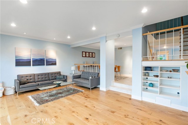 Wide-plank wood floors and recessed lighting add style and function to the living area.  Extra shelves under stair case provide interest.