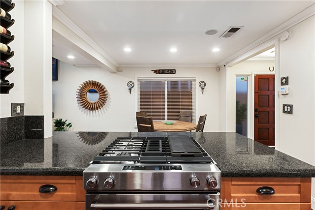 The gorgeous kitchen is upgraded with custom cabinetry, dark granite countertops and peninsula, newer stainless steel range cooktop, and stainless steel refrigerator and dishwasher.