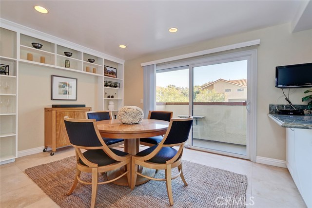 Spacious breakfast nook has floor-to-ceiling built-in shelving, recessed lighting, and adjacent balcony for BBQing.