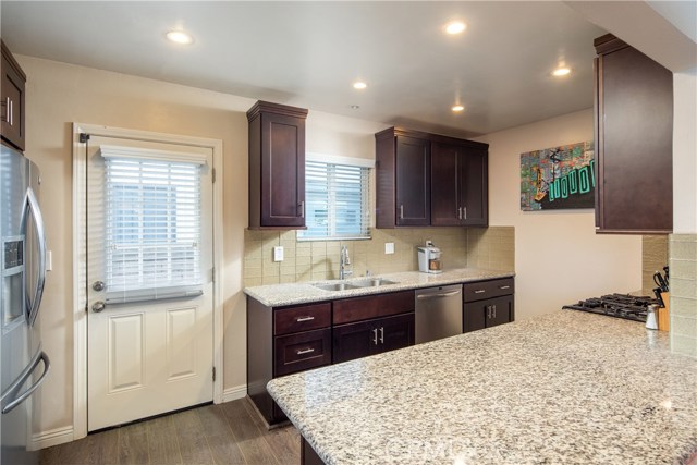 The gorgeous kitchen with newer stainless steel appliances, rich wood cabinetry, granite counter tops, and glass tiled backsplash.