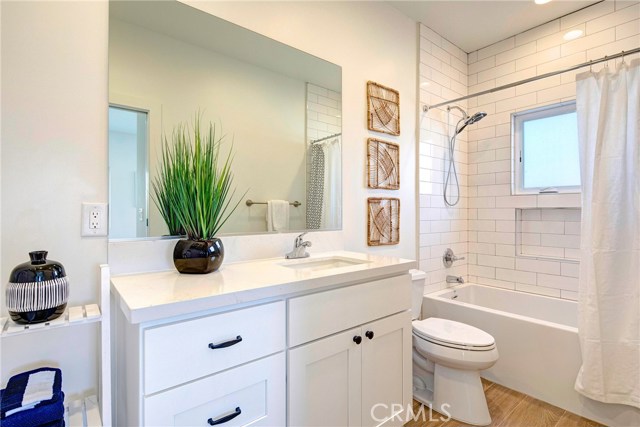 Upstairs front bathroom, en-suite.  Subway tile, porcelain wood-like tile flooring, Calico Quartz countertops.