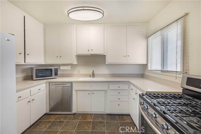 Kitchen with stainless 5 burner range, dishwasher and corian counters