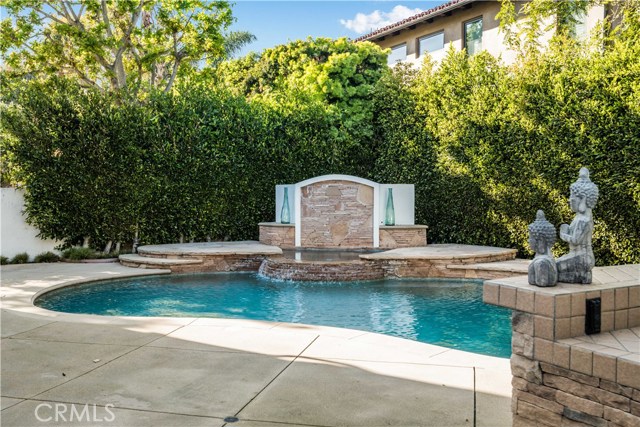 The tropical backyard includes sparkling pool with water feature and a bubbling spa