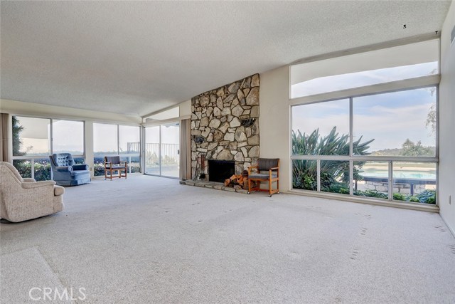 LIGHT AND BRIGHT LIVING ROOM OVER LOOKING THE SWIMMING POOL, BACKYARD, FIRE PIT, AND VIEW OF THE HARBOR, AND CITY/MOUNTAIN VIEWS. COZY PALOS VERDES STONE FIREPLACE.