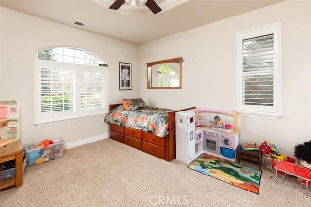 Bedroom with ceiling fan, plantation shutters.