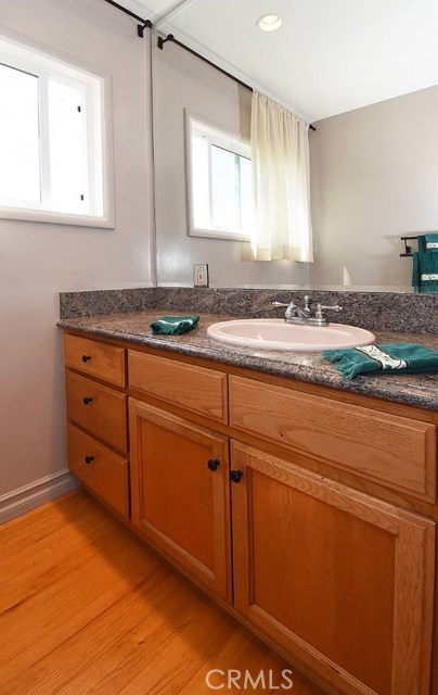 Remodeled master bath with beautiful wood cabinets and flooring and granite counter.