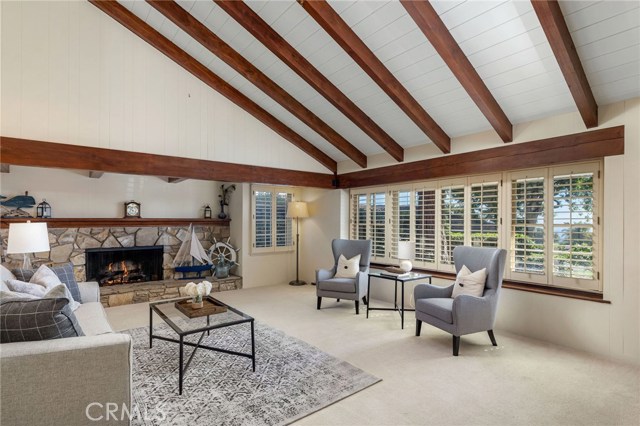 The ocean view living room brings gorgeous golden sunsets in a picturesque setting. With a large warm fireplace, exposed rich wood beam ceiling, and the open style space adds to the highlights of the home.