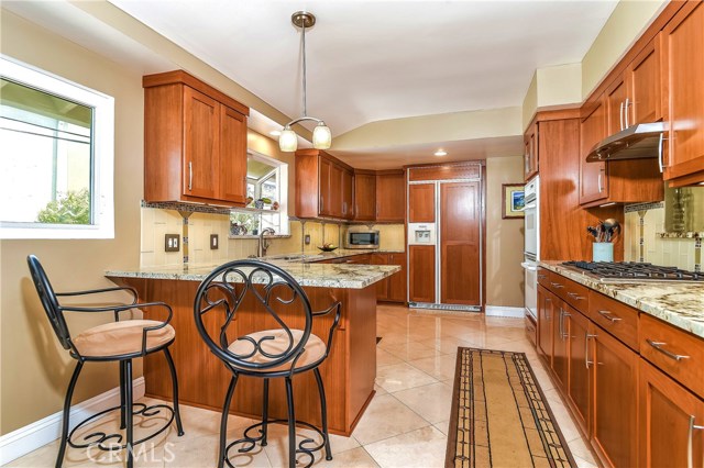 The kitchen has beautiful thick slab granite counter tops, a custom designed glass tile backsplash, travertine floors, and a large garden window.