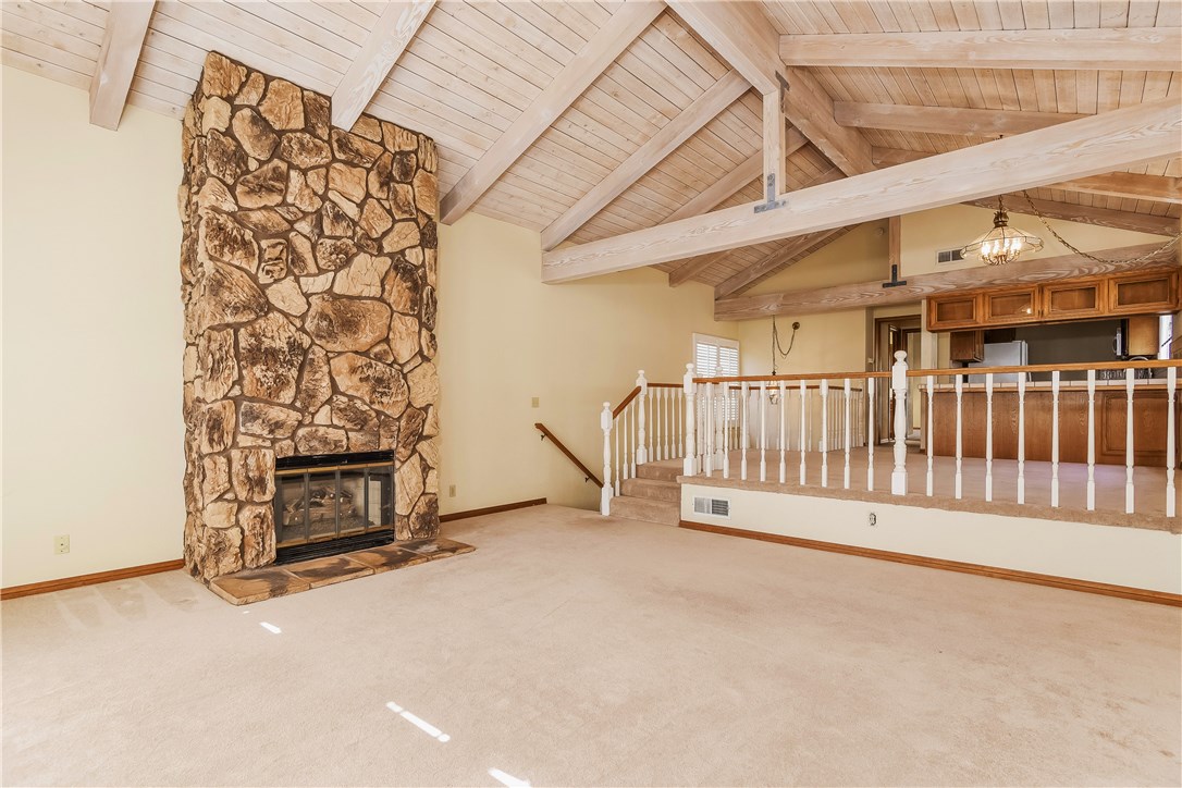 The living room has a large floor to ceiling stone fireplace and a vaulted and trussed, light washed solid wood cathedral ceiling runs throughout the upper level of the home, offering a feeling of spaciousness and well built quality.