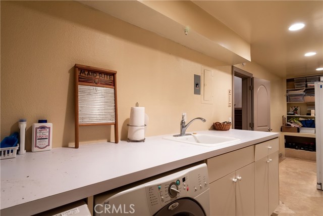 Downstairs Oversized laundry room with built-in shelving and utility sink.