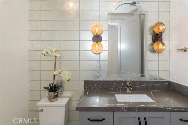 powder bath at entry level, gorgeous copper lighting, mirrored wall and cement tile floor