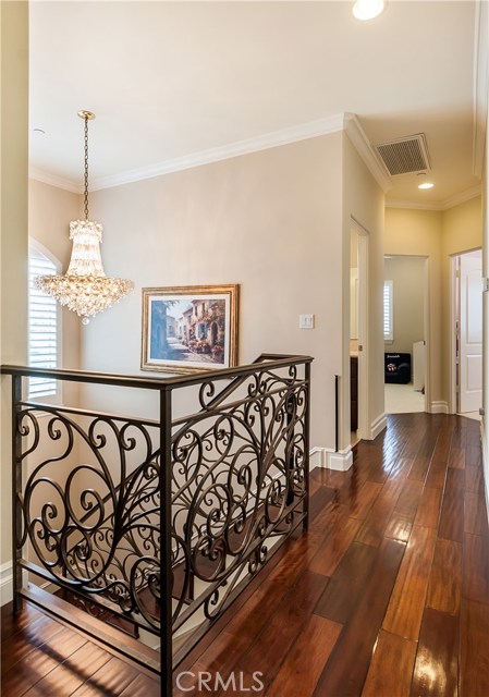 The staircase features Brazilian cherry wood stairs, a stunning chandelier and an intricate wrought iron railing.