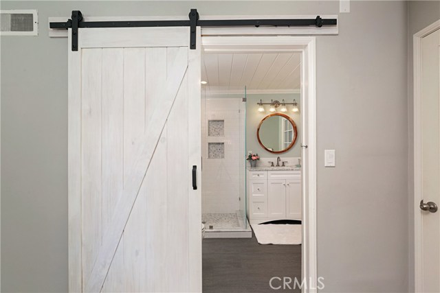 Remodeled master bathroom with frameless, enclosed shower, and rolling barn style door.