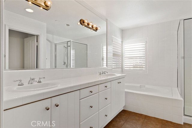 Large master bathroom with a dual vanity, lots of drawers, a full bathtub and a separate shower.