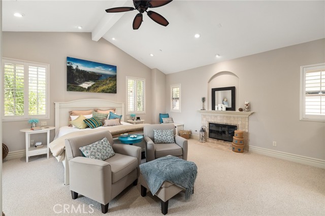 Primary bedroom with beamed ceilings, fan and fireplace