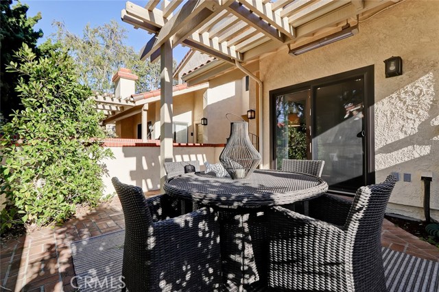 Patio includes brick flooring and overhang wood arbor.