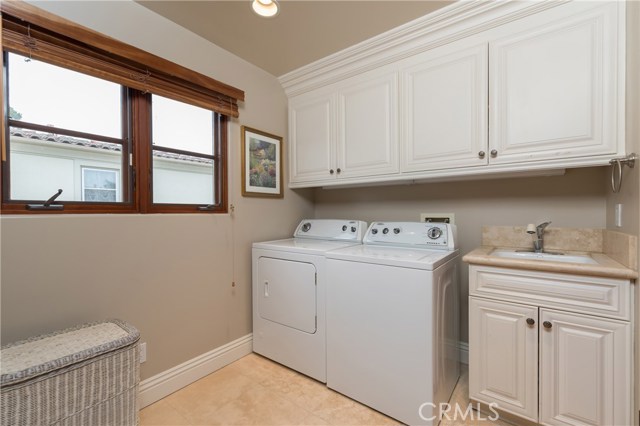 Large laundry room with utility sink and cabinetry is conveniently located upstairs off the the main bedroom areas.