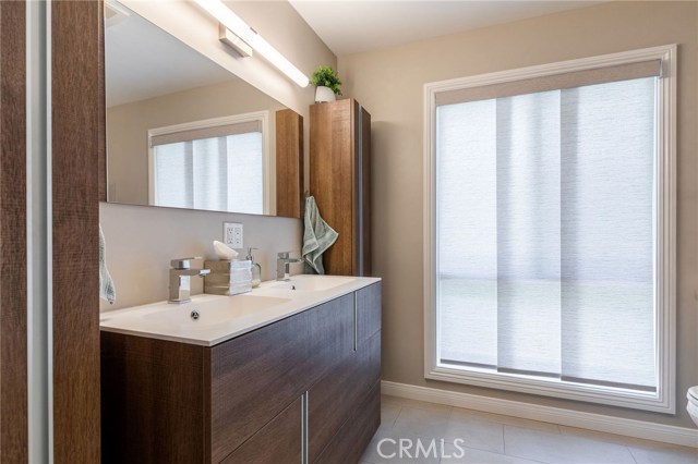 Classy master bathroom has large vanity with 2 sinks, side cabinets, tiled floors and large window.
