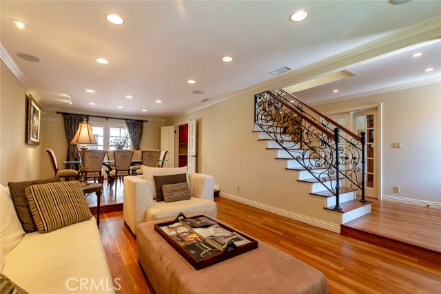 Living room with separate dining area in background.  Staircase iron railing is custom.  French doors next to staircase lead to office.