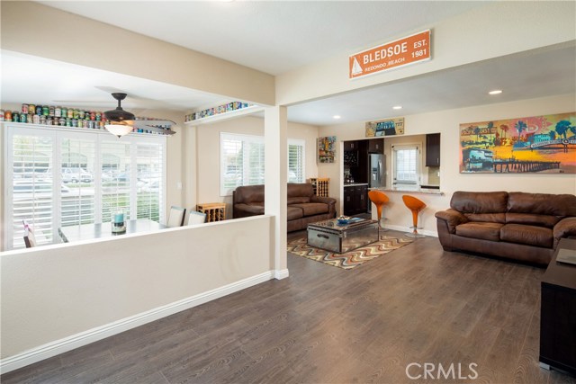 The living room is a bright an open space with wood-style floors, recessed lighting, and plantation shutters.
