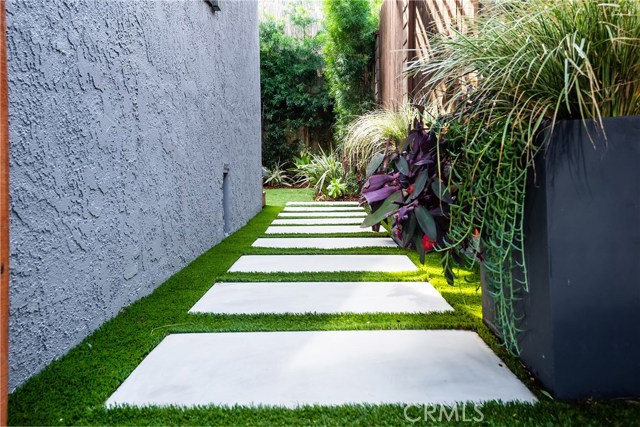 MODERN CONCRETE PADS LEAD YOU TO THE MAIN ENTRANCE OF THE HOME UNDER A WOODEN TRELLIS.