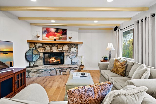 Spacious family room with large wood burning fireplace and wood beams in ceiling.