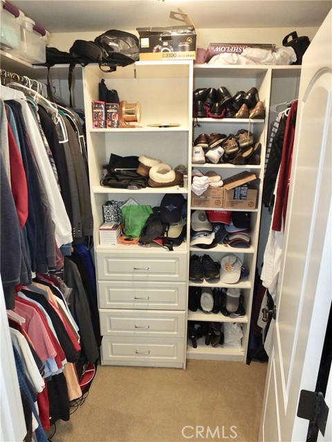 Walk-In Closet in Primary Bedroom featuring double hanging rods, shelves and drawers.