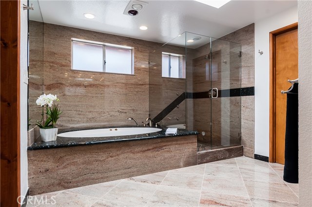 Beautiful granite finishes around spa tub and frameless glass shower enclosure.